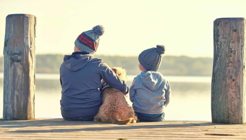 Geschisterkinder mit Hund am See