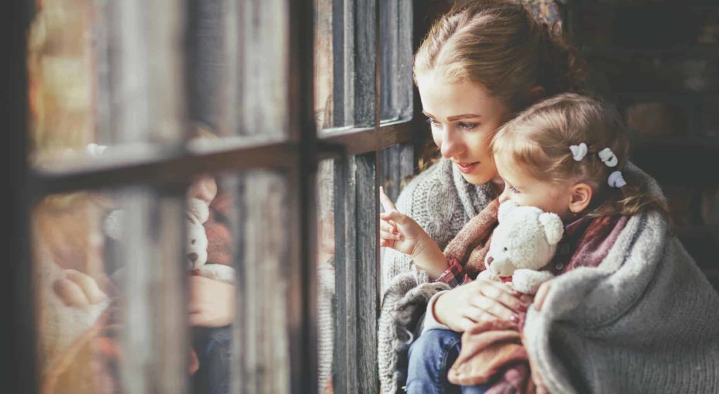 Alleinerziehende Mutter und Tochter schauen aus dem Fenster