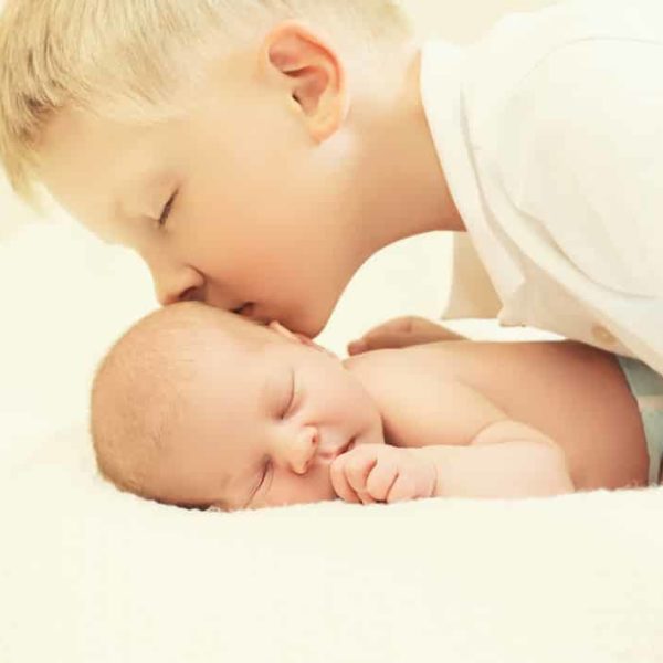 Älterer Bruder küsst Säugling - Geschwisterkinder