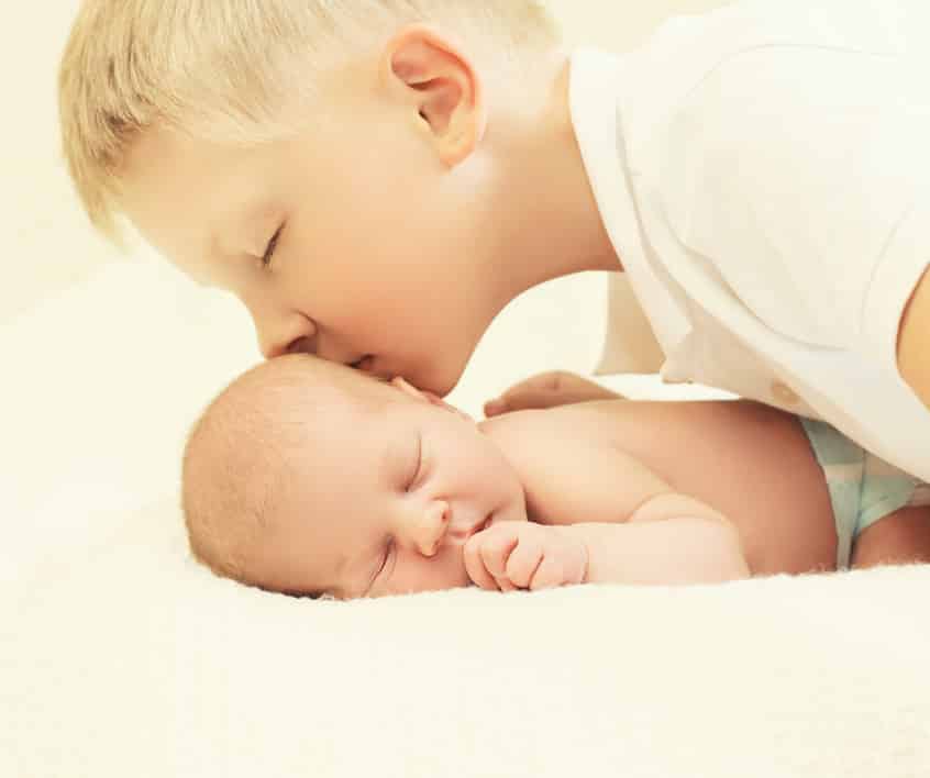 Älterer Bruder küsst Säugling - Geschwisterkinder