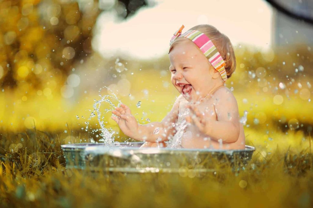 Baby spielt bei Hitze mit Wasser