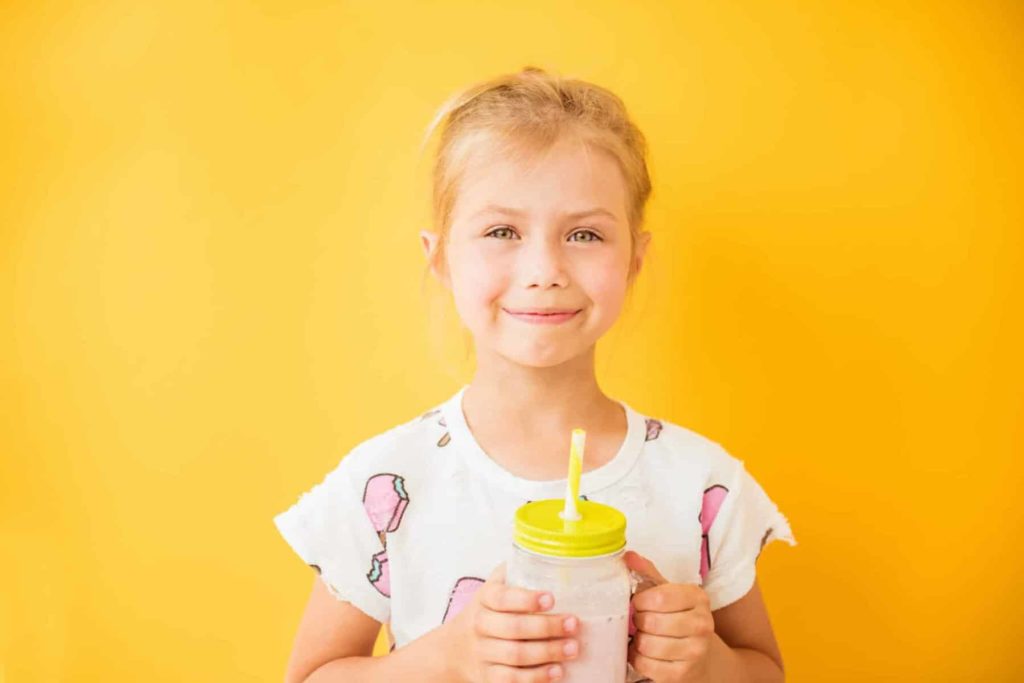 Junges Mädchen trinkt Erdbeermilch