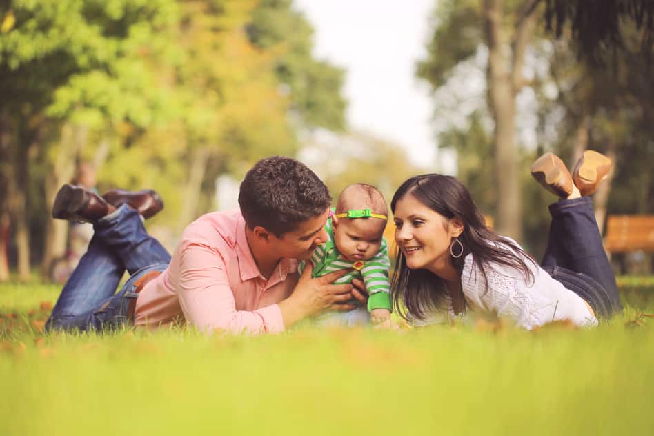 Partnerschaft: Eltern mit Baby sitzen im Gras