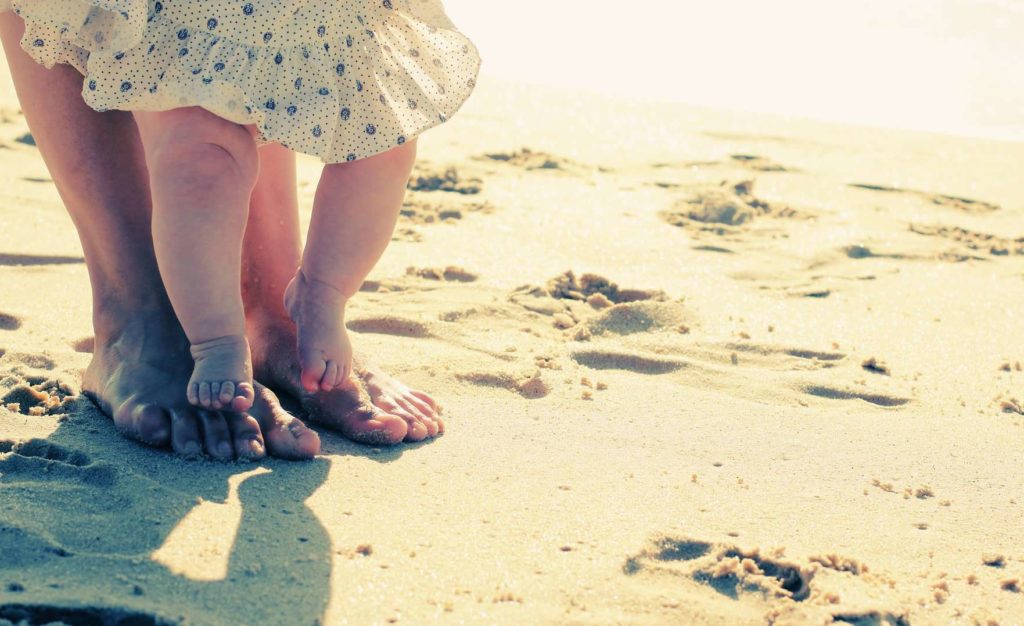 Baby spaziert im Sand am Strand