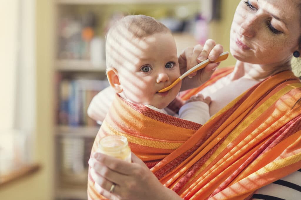 Baby bekommt Beikost im Tragetuch