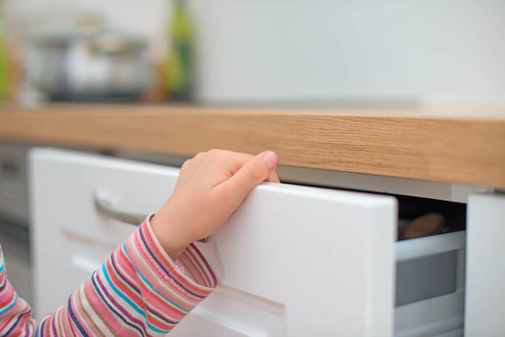 Kind klemmt sich die Finger in Küchenschrank ein.