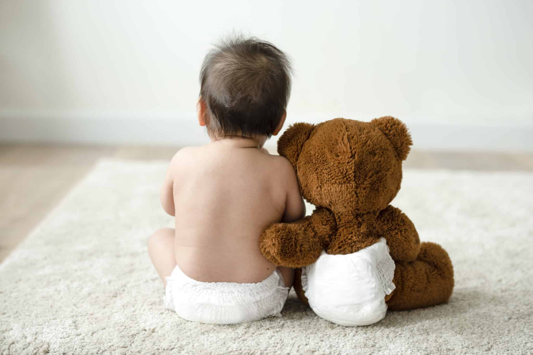 Baby und Teddybär in Windeln