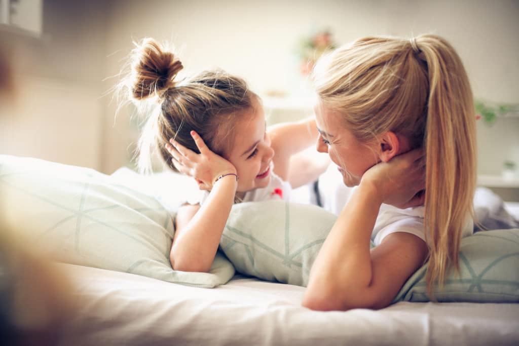 Mama und Tochter reden im Bett