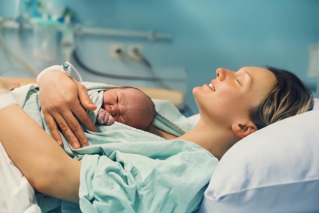 Das erste Mal Kuscheln nach der Geburt. Mutter hat ihr Baby glücklich im Arm.