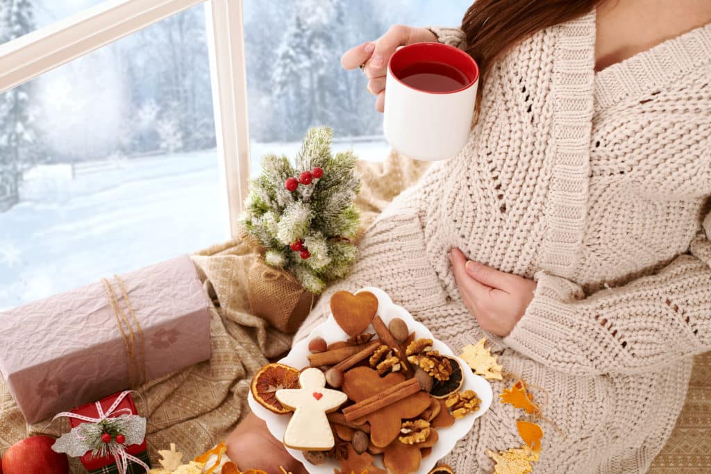 Schwangere Frau mit Zimtplätzchen und Wweihnachtstee