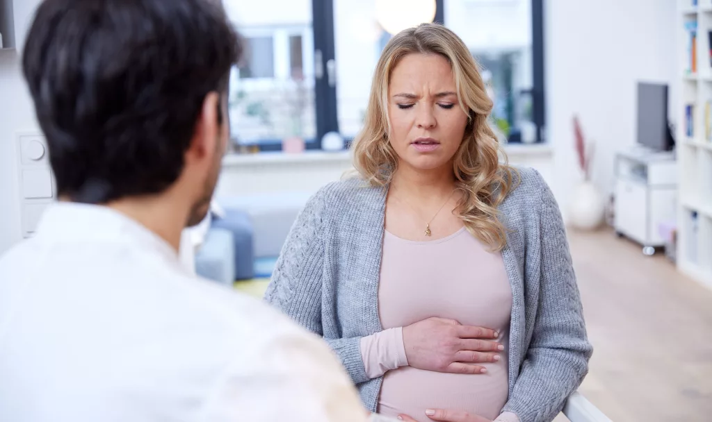 Frau mit Schwangerschaftsübelkeit beim Arzt.