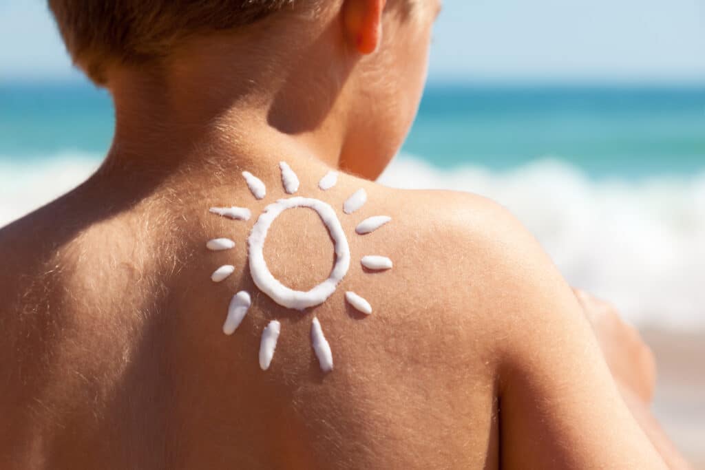 Sonnencreme auf Rücken von kleinem Jungen.