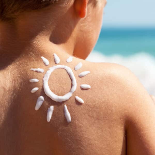 Sonnencreme auf Rücken von kleinem Jungen.