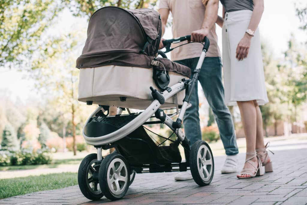 Kinderwagen wird von Eltern geschoben.