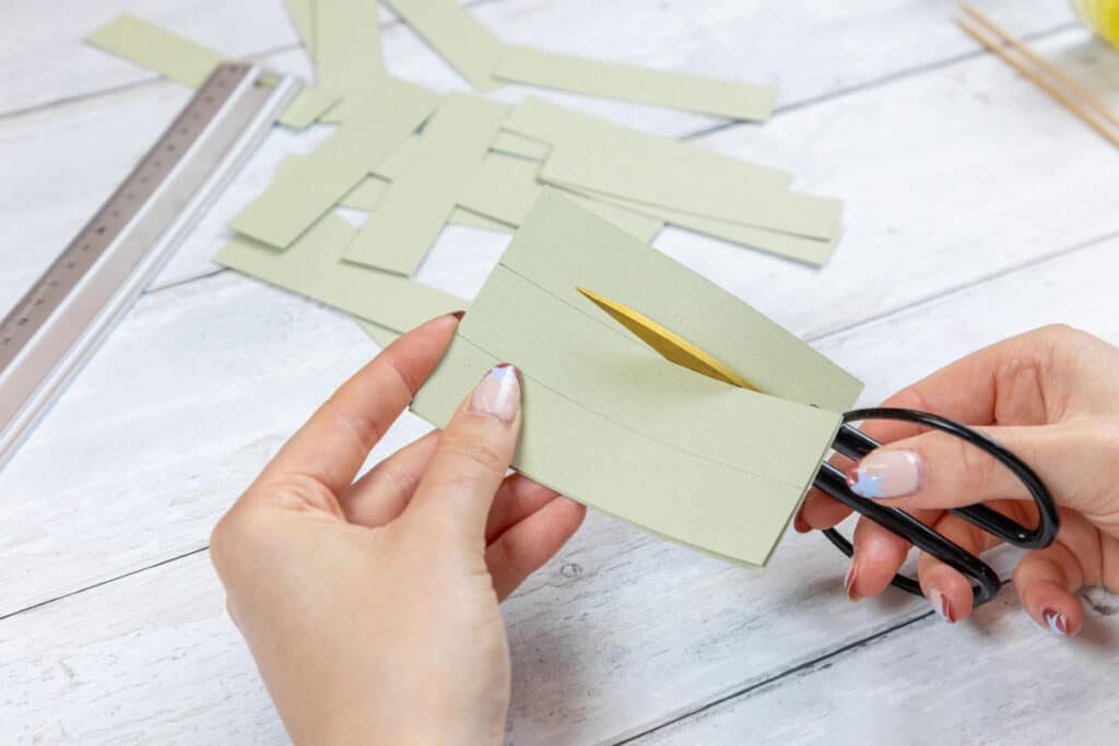 Das Tonpapier längs halbieren und jede Hälfte in 12 etwa 2,5 cm breite Streifen schneiden.
Foto: DJD/Pilot Pen