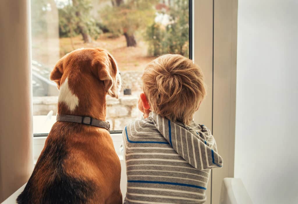 Hund und Kind warten gemeinsam darauf, die Ostereiersuche starten zu dürfen.